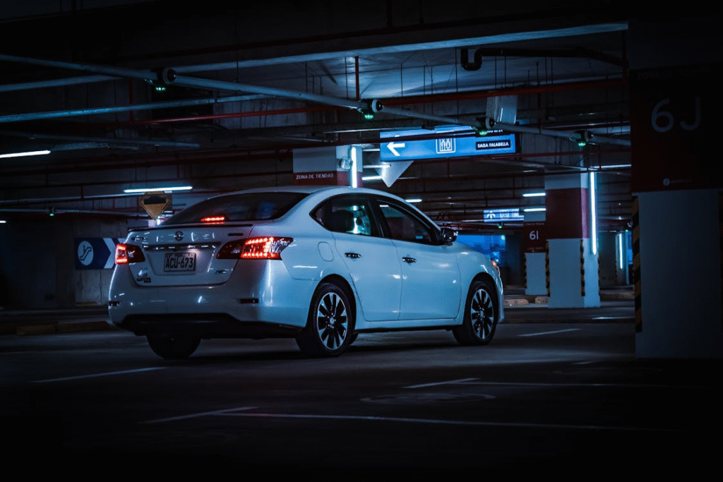 A car with lights on parked in a public area