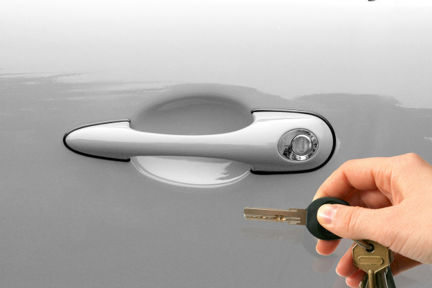 Hand holding key near white car door